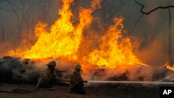 FILE - Firefighters battle a wildfire along Highway 71 near Smithville, Texas, Sept. 5, 2011. 