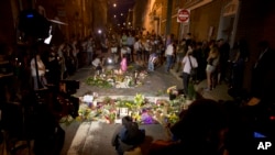 Cahaya kamera TV menerangi tumpukan bunga tanda belasungkawa dalam doa bersama di Charlottesville, Virginia, Minggu, 13 Agustus 2017 untuk memperingati korban luka dan meninggal dalam aksi protes sehari sebelumnya. 