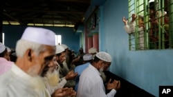 Children of Rohingya refugees watch from a window as elders pray inside a mosque on Eid al Adha at Kutupalong refugee camp, Bangladesh, Wednesday, Aug. 22, 2018. (AP Photo/Altaf Qadri)