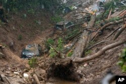 Cars and a large tree are seen in a debris trail in the aftermath of a mudslide that destroyed three homes on a hillside in Sausalito, Calif., Feb. 14, 2019.
