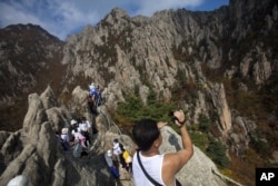 FILE – A North Korean man records video while climbing his country’s Mount Kumgang in 2012.