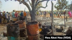 People walk past the charred remains of a shop in a market in Aweil, South Sudan, that was gutted by an overnight fire.