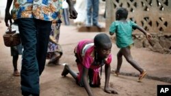 File - In this April 14, 2014 photo, Hamamatou Harouna, 10, crawls to the restroom on the grounds of the Catholic Church where she and hundreds of others found refuge in Carnot, Central African Republic.