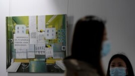 Visitors wearing face masks hang out near an art piece painted by Chinese artist Yang Qian, depicting a hospital reception counter plastered with instructions for patients, as they visit a studio in Wuhan in central China's Hubei province