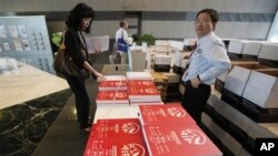 A prospective investor, left, takes a copy of the AIA (American International Group Inc) initial public offering (IPO) prospectus book at a bank in Hong Kong, 18 Oct 2010