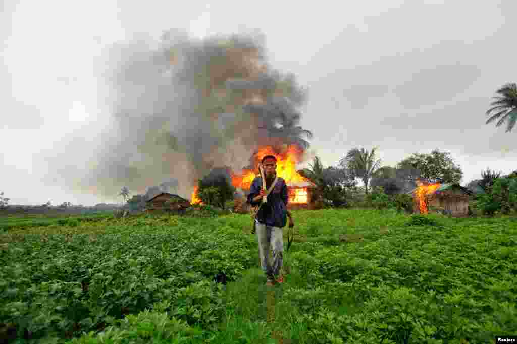 June 10: An ethnic Rakhine man with homemade weapons walks in front of houses that were set on fire during fighting between Buddhist Rakhine and Muslim Rohingya communities in Sittwe, Burma.