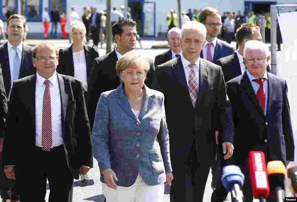 Heidenau major Juergen Opitz, German Chancellor Angela Merkel, Saxony State Prime Minister Stanislaw Tillich and president of the German Red Cross Rudolf Seiters (left to right) arrive for statements after their visit to an asylum center in the eastern German town of Heidenau, near Dresden, Aug. 26, 2015.