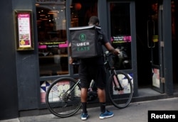 An UberEATS food delivery courier prepares his bike in London on September 7, 2016. Uber is advertising to fill jobs from general managers to bike couriers.