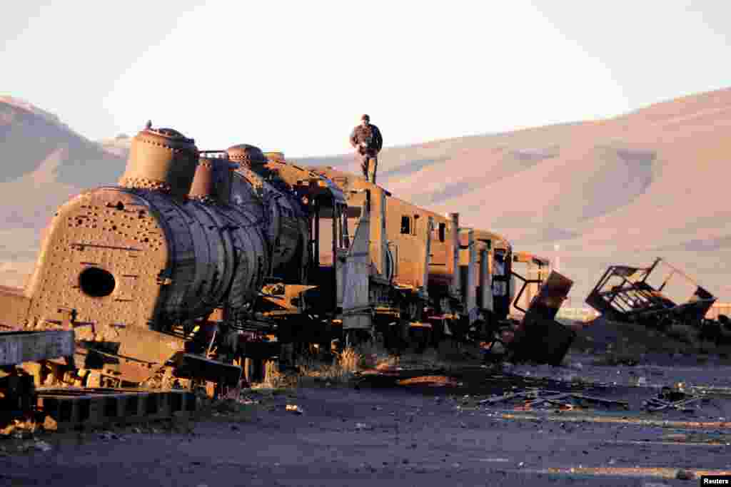 A man stands on an old train of the Bolivian Railways Company from 1870-1900 at the train cemetery in Uyuni, Potosi.