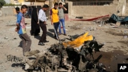 Onlookers inspect the site of a car bomb attack in the capital's eastern Mashtal neighborhood, Iraq, Oct. 27, 2013.