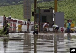 7月23日工人们在房山区一个公路收费站外堆沙包