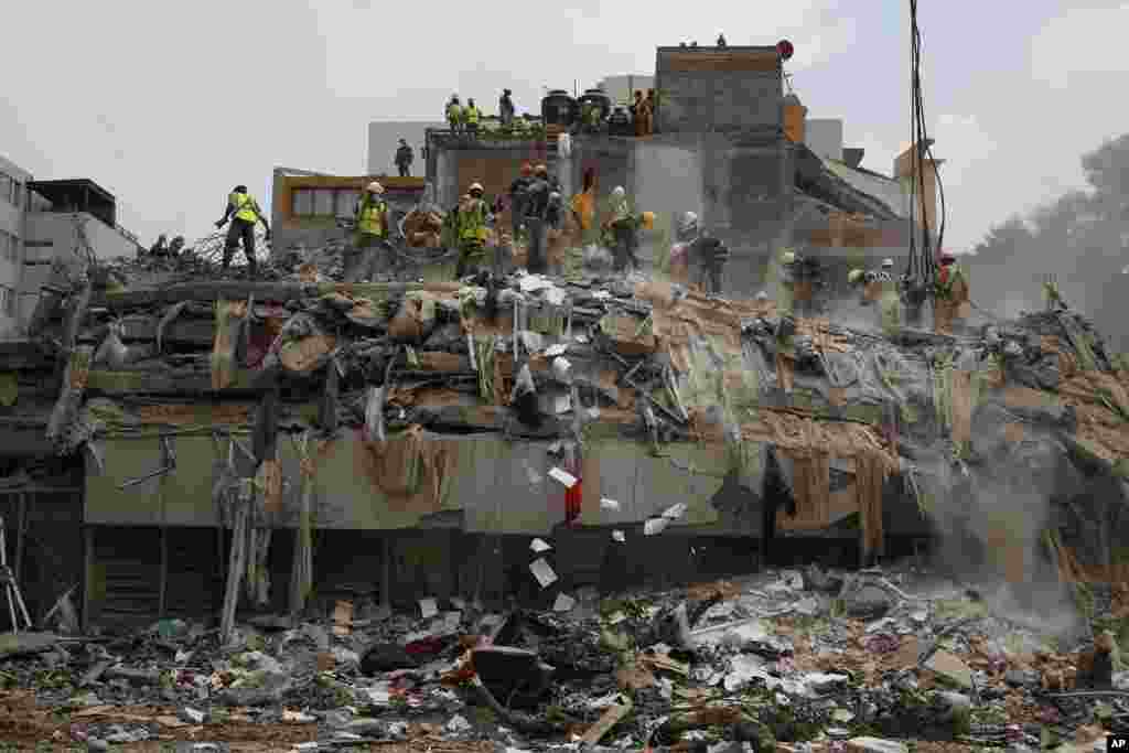 Workers shovel papers and debris off the top of the rubble of a building that collapsed in last week&#39;s 7.1 magnitude earthquake, at the corner of Gabriel Mancera and Escocia streets in the Del Valle neighborhood of Mexico City, Sept. 25, 2017.