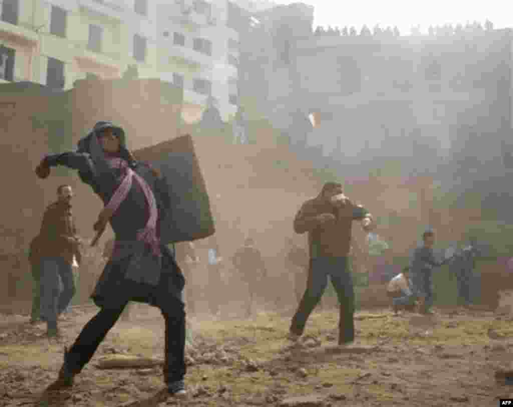 Anti-government protestors throw stones during clashes in Cairo, Egypt, Thursday, Feb. 3, 2011. Another bout of heavy gunfire and clashes erupted Thursday around dusk in the Cairo square at the center of Egypt's anti-government chaos, while new looting an