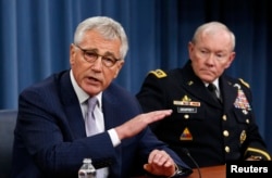 U.S. Secretary of Defense Chuck Hagel (L) speaks next to Chairman of the Joint Chiefs of Staff General Martin Dempsey during a press briefing at the Pentagon in Washington, Aug. 21, 2014.