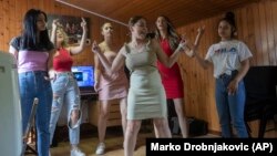 Zlata Ristic, 27, center, Elma Dalipi, 14, left, Silvia Sinani, 24, 2nd left, Dijana Ferhatovic, 18, 3rd left, Zivka Ferhatovic, 20, 2nd right, and Selma Dalipi, 14, members of the Pretty Loud band in Belgrade, Serbia, Wednesday, June 16, 2021. (AP Photo/Marko Drobnjakovic)