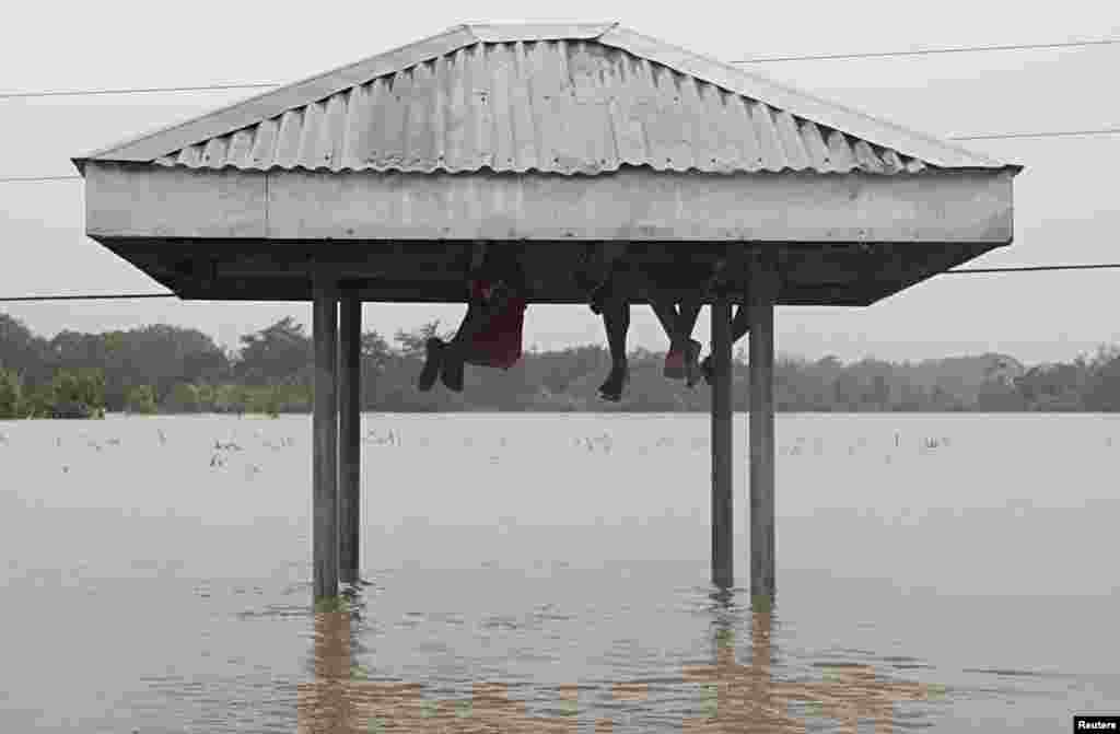 Residents take shelter under the roof of a bus stop on a flooded highway after tropical storm Linfa hit Luna, La Union in northern Philippines.