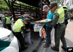 En esta foto del 22 de febrero de 2018, agentes de la policía colombiana detienen a migrantes venezolanos que no tienen identificación y permisos para vender productos, en Cúcuta, Colombia.