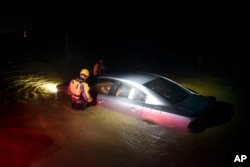 Rescue staff from the Municipal Emergency Management Agency investigate an empty flooded car during the passage of Hurricane Irma through the northeastern part of the island in Fajardo, Puerto Rico, Sept. 6, 2017.