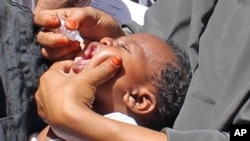 In this May 28, 2013 photo, Somali vaccination workers give an anti-polio drop to a child, in Mogadishu. Somalia. 