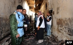 FILE - Afghan (L) talks to staff members in a charred corridor of the damaged Medecins Sans Frontieres (MSF) hospital in northern Kunduz.