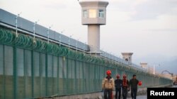 几个工人从新疆再教育营的外围围栏走过。（2018年9月4日）