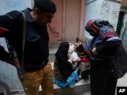 Seorang petugas polisi berjaga saat petugas kesehatan memberikan vaksin polio kepada seorang anak di Peshawar, Pakistan, Kamis, 30 Januari 2020. (Foto: AP)