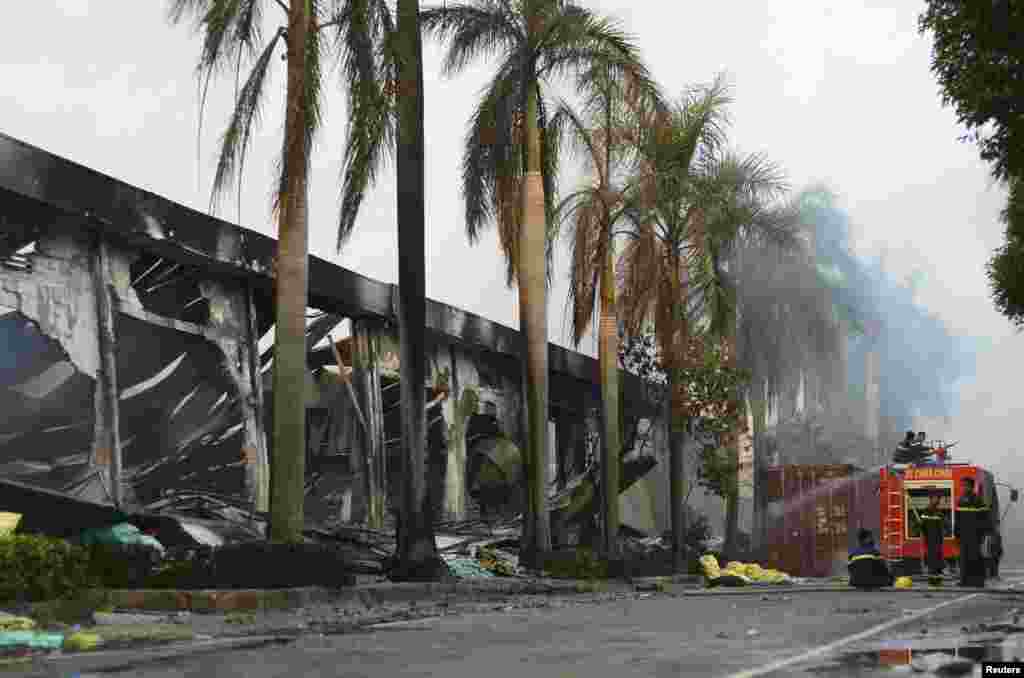 Firefighters rest near a damaged Chinese owned shoe factory in Vietnam&#39;s southern Binh Duong province. Foreign factories in industrial zones were set on fire and rampaged in an angry reaction to Chinese oil drilling in a part of the South China Sea claimed by Vietnam, official said.