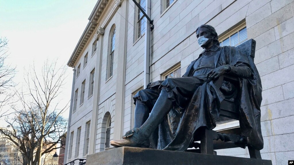 哈佛大学学生陆续搬离宿舍。图为哈佛大学一座地标雕塑，疫情之下有人为它也戴上了口罩。（2020年3月14日）(photo:VOA)