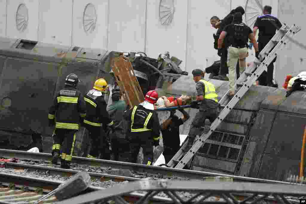 Una mujer es evacuada por los equipos de rescate en la estación de Angrois, en las afueras de Santiago de Compostela donde descarrriló el tren de alta velocidad de Alvia en España.