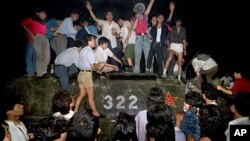 FILE - Civilians with rocks stand on a government armored vehicle near Chang'an Boulevard in Beijing as violence escalated between pro-democracy protesters and Chinese troops, leaving hundreds dead, June 4, 1989.