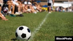 Spectators on the sidelines watching a soccer game.