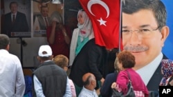 People walk past a poster of Turkey's Prime Minister and leader of the Justice and Development Party (AKP) Ahmet Davutoglu (R) in Istanbul, Turkey, June 5, 2015. 
