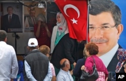 FILE - People walk past a poster of Turkey's Prime Minister and leader of the Justice and Development Party (AKP) Ahmet Davutoglu (R) in Istanbul, Turkey, June 5, 2015.