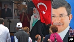 Saylovchilar AKP yetakchisi Ahmet Davutoglu surati oldida. Istanbul, 5-iyun 2015-yil. 