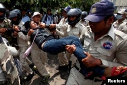 FILE - Cambodian security officers carry off a woman during a protest near the National Assembly in Phnom Penh, Aug. 27, 2014. Boeung Kak Lake residents and other communities who are embroiled in land disputes gathered to appeal for help from the government.