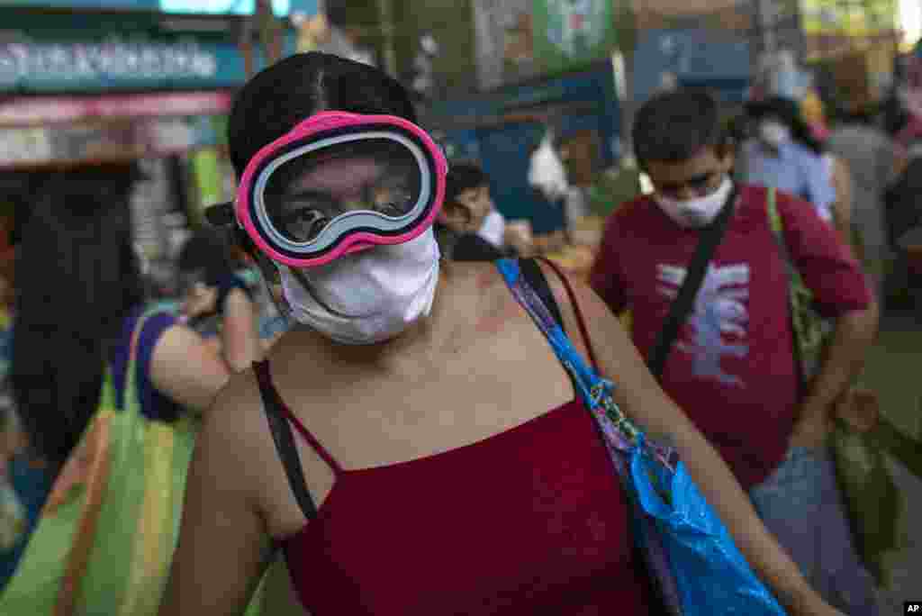 Una mujer usa una máscara de buceo y una máscara quirúrgica como precaución contra la propagación del nuevo coronavirus, mientras compra alimentos en un mercado popular en Lima, Perú, el lunes 23 de marzo de 2020.&nbsp;