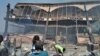 People stand in front of fire-damaged Iron Market in Port-au-Prince, Haiti, Feb. 13, 2018. (F. Lisené/VOA Creole)