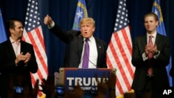 Republican presidential candidate Donald Trump, is flanked by his two sons, Donald Trump Jr., left, and Eric, while speaking at a caucus night rally Tuesday, Feb. 23, 2016. (AP Photo/Jae C. Hong)