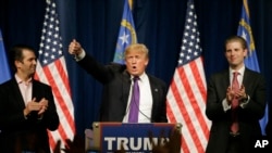 Republican presidential candidate Donald Trump, is flanked by his two sons, Donald Trump Jr., left, and Eric, while speaking at a caucus night rally Tuesday, Feb. 23, 2016.