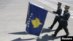 Members of Kosovo Security Force march with a flag of Kosovo (front)