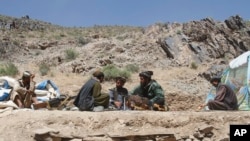 In this May 27, 2016, photo, Taliban fighters eat lunch in Shindand district of Herat province, Afghanistan.