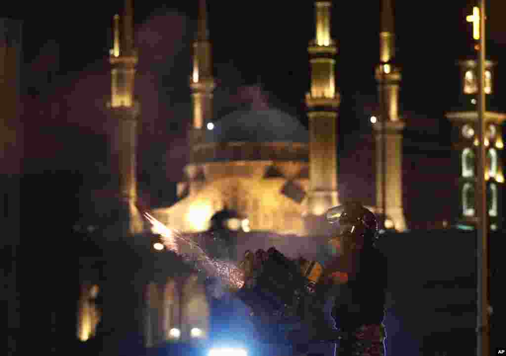 A riot police officer fires tear gas at anti-government protesters trying to enter parliament square in downtown Beirut, Lebanon, Dec. 14, 2019.