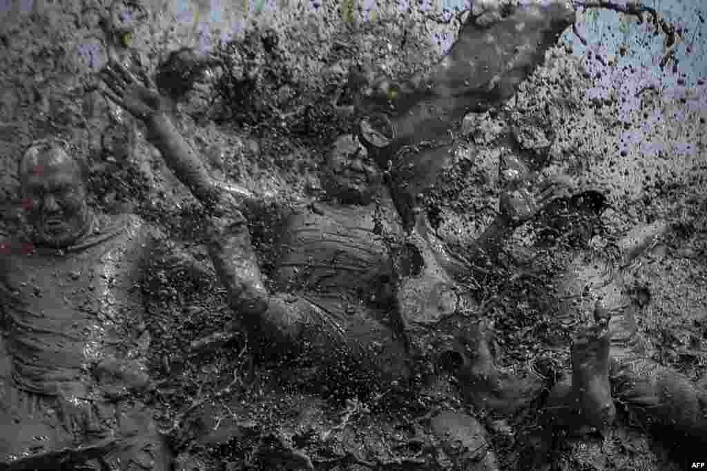 Mud-covered farmers play in a rice paddy field during &quot;National Paddy Day&quot;, which marks the start of the annual rice planting season, in Tokha village on the outskirts of Kathmandu, Nepal, June 29, 2021.