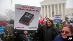 Beth Corbin holds a poster during a demonstration in front of the Supreme Court in Washington, Tuesday, March 25, 2014, as the court heard oral arguments in the challenges of President Barack Obama's health care law requirement that businesses provide their female employees with health insurance that includes access to contraceptives. 