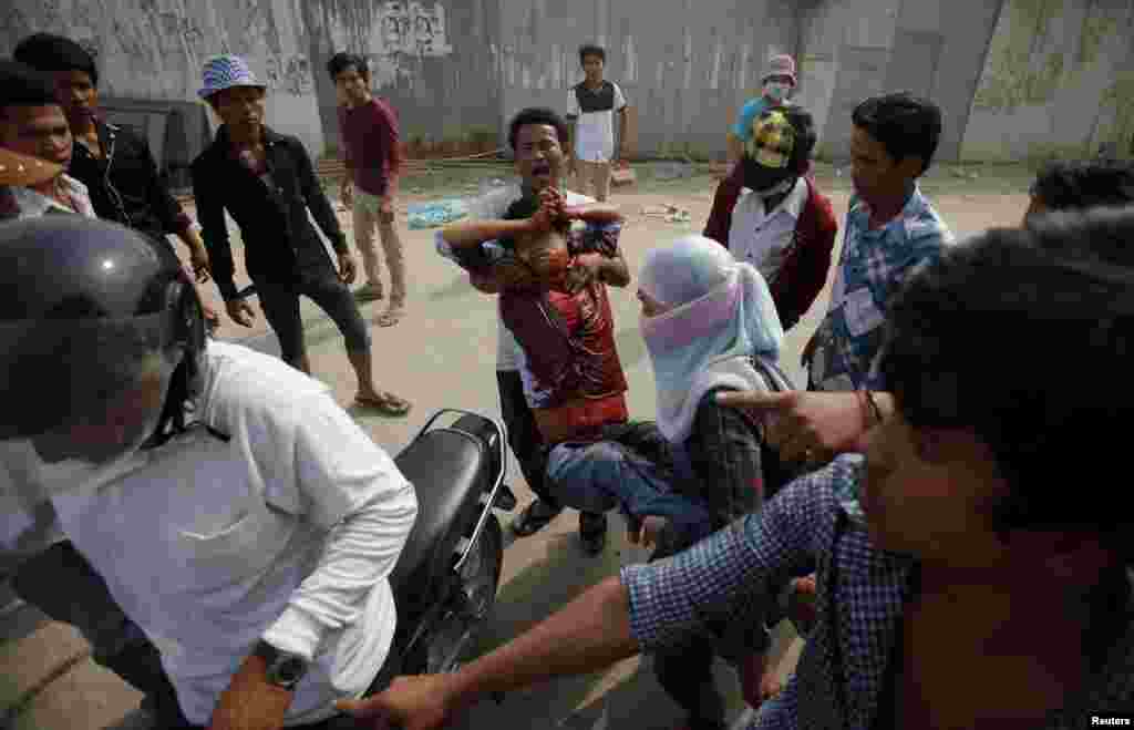 An injured garment worker is helped by his colleagues after clashes broke out during a protest in Phnom Penh, Jan. 3, 2014.