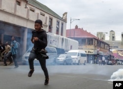 Members of the ANC Youth League flee from teargas and rubber bullets fired by police, at the end of a march by the main opposition Democratic Alliance party in Johannesburg, April 7, 2017.