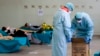 Paramedis membawa kotak limbah medis berbahaya sementara pasien virus corona berbaring di tempat tidur di Rumah Sakit Brescia, Italia, Kamis, 12 Maret 2020. (Foto: AP/Luca Bruno)