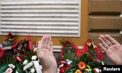 FILE - A Bosnian man prays in front of a memorial plague during the 13th anniversary of the shelling from neighboring hills by the Bosnian Serb forces in the capital Sarajevo, Aug. 28, 2008.