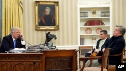 President Donald Trump speaks on the phone with Prime Minister of Australia Malcolm Turnbull, with National Security Adviser Michael Flynn, center, and chief strategist Steve Bannon, right, in the Oval Office of the White House, Jan. 28, 2017, in Washington.