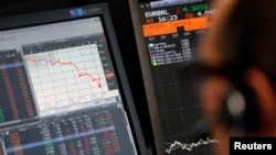 Un directeur des ventes est assis près d'un écran qui montre la baisse de valeur des actions françaises du CAC 40 chez Allianz Global Investors à Paris, France, 24 août 2015. REUTERS / Regis Duvignau